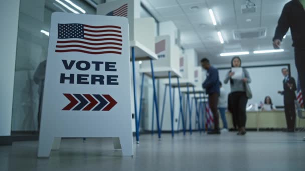 床にサインを投票してください 複数の民族アメリカ市民が投票所のブースで投票する アメリカ合衆国選挙の日 アメリカ合衆国大統領候補の政治的競争 市民としての義務 — ストック動画