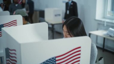 Asya kökenli kadın Amerikan vatandaşı oy kullanma merkezindeki kabinde oy kullanıyor. Birleşik Devletler 'de Ulusal Seçim Günü. ABD başkan adaylarının siyasi ırkları. Vatandaşlık görevi ve vatanseverlik kavramı.