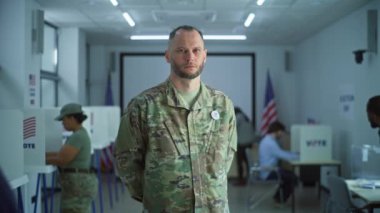 Erkek askerin portresi, Amerika Birleşik Devletleri seçmeni. Kamuflaj üniformalı bir adam modern bir seçim merkezinde duruyor ve kameraya bakıyor. Oy verme kabinleri olan bir arka plan. Vatandaşlık görevi kavramı.