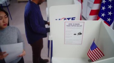 Asyalı bir kadın oy verme merkezine gelir, seçim yapar ve kağıt bülten doldurur. Amerika Birleşik Devletleri 'ndeki Ulusal Seçim Günü' nde Amerikan vatandaşı. Vatandaşlık görevi ve vatanseverlik.