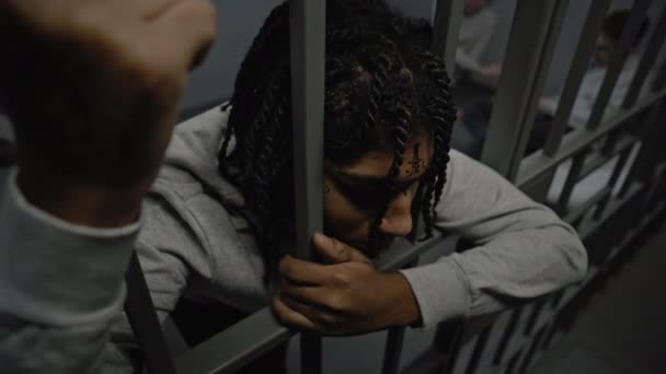 Zdenerwowany Afroamerykanin Nastoletni Więzień Siedzi Więzieniu Trzyma Metalowe Kraty Młodzi — Wideo stockowe