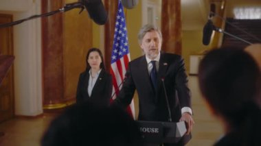 Gazeteciler, Amerika Başkanı 'nın basın toplantısında ilham verici siyasi konuşmasını bitirdiğini alkışlıyorlar. Politikacı Beyaz Saray 'da basın için röportaj veriyor. Arka planda Amerikan bayrakları.