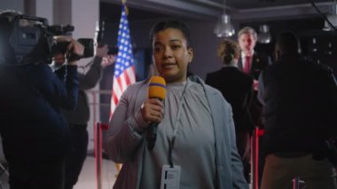 Kadın gazeteci, Amerikalı politikacı veya ABD Başkanı 'nın politik televizyon programı için düzenlediği basın toplantısını yönetiyor. Afrikalı Amerikalı spiker, hükümet binasından canlı olarak son dakika haberi bildirdi.