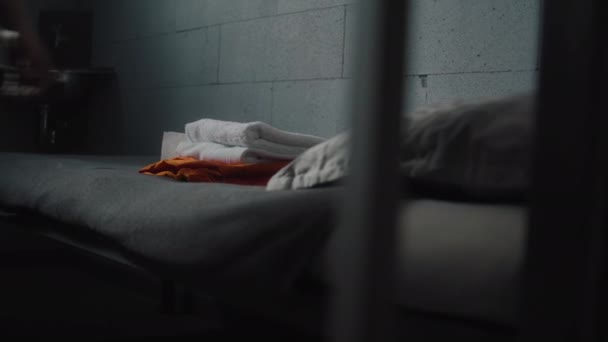 囚犯把橙色制服和浴室配件放在牢房的床上 犯人在监狱服刑 拘留中心或教养所 透过金属棒观看 — 图库视频影像