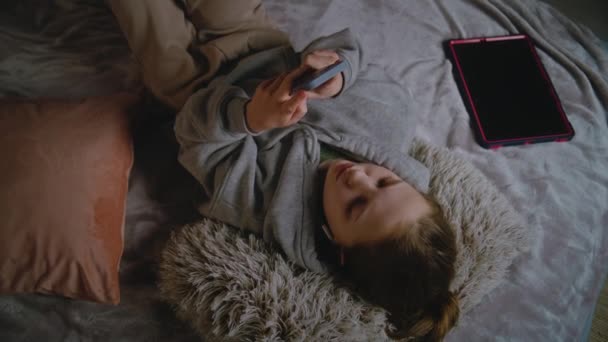 Молодая Девушка Наушниках Лежит Дома Кровати Слушает Музыку Пользуется Интернетом — стоковое видео