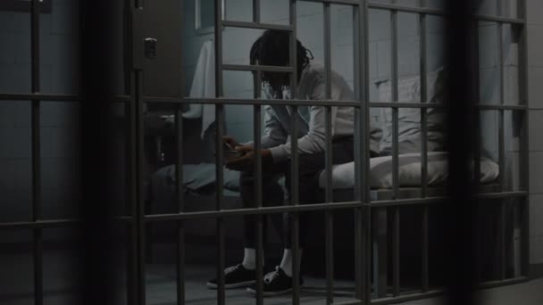 Młody Afroamerykanin Zjada Obrzydliwe Więzienne Jedzenie Żelaznej Miski Siedzącej Łóżku — Wideo stockowe