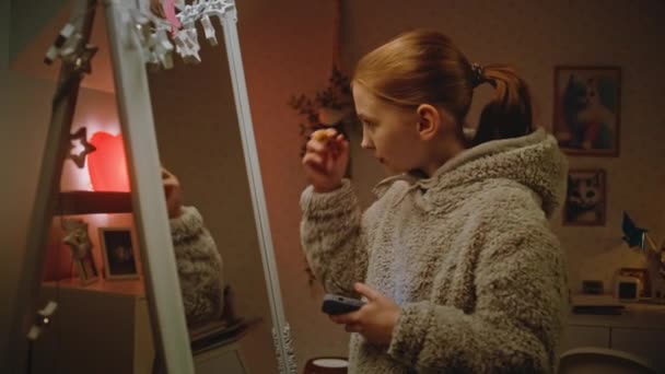 若い白人美女は居心地の良い寝室の鏡の前に化粧をして スマートフォンを使って写真を撮ります 十代の女の子は夜に家で余暇を過ごしています ライフスタイルの概念 — ストック動画