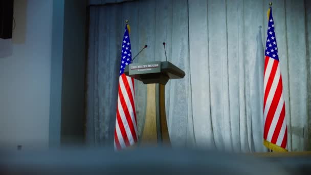 プレス キャンペーン ルームで ホワイトハウスのアメリカ合衆国大統領の政治演説のためのトリビューン 木製の会議の議論はステージ上のマイクと立っています 背景にあるアメリカの国旗 — ストック動画