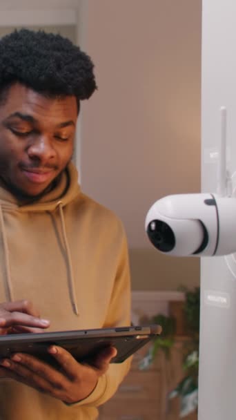 アフリカ系アメリカ人男性は デジタルタブレットを使用して自宅でAi認識を備えたセキュリティカメラを設置しています 3D円レンダリングはCctvカメラとの無線インターネット接続を示します Vfxアニメーション バーティカルショット — ストック動画