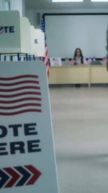 Afrika kökenli Amerikalı bir adam, erkek seçmen oy kullanma merkezinde kayıt olmak için kadın sandık görevlisine gider, oy vermek için kağıt oy kullanır. Amerika Birleşik Devletleri 'nde Ulusal Seçim Günü. Yurttaşlık görevi.