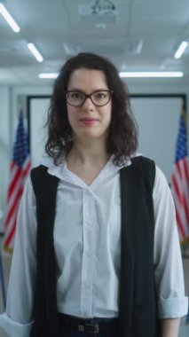 Amerikalı kadın seçmen ya da sandık memuru kameraya konuşuyor, oy kullanma çağrısı yapıyor. Birleşik Devletler 'de Ulusal Seçim Günü. Oy kullanma merkezinin arka planında oy kullanma kabinleri var. Vatandaşlık görevi ve vatanseverlik.