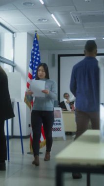 Çok ırklı seçmenler ya da Amerikan vatandaşları oy kullanma merkezindeki kabinlerde oy kullanıyorlar. Asyalı kadın ve Afro-Amerikan kadın ordusu oy pusulalarını kutuya koydu. Birleşik Devletler 'de Ulusal Seçim Günü. Demokrasi kavramı.