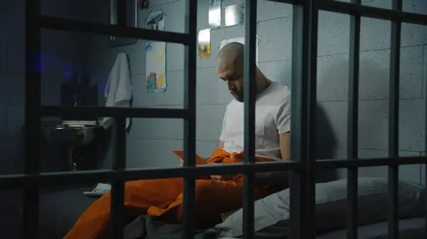 Mannelijke Gevangene Oranje Uniform Zit Bed Gevangenis Cel Kijkt Naar — Stockfoto