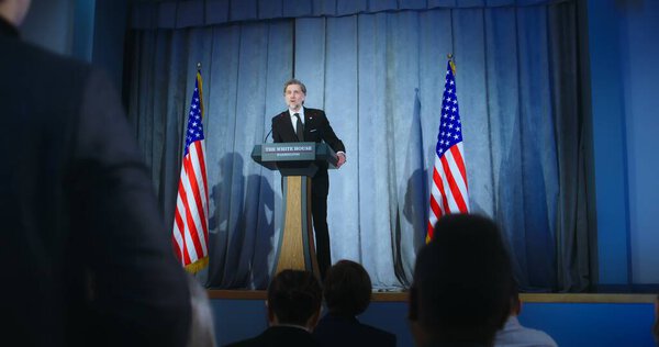 Presidential of USA candidate delivers campaign speech, answers questions, gives interview. American republican politician performs at meeting with press. Election day. Backdrop with American flags.