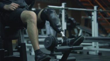 Motivasyonlu sporcu, modern fitness merkezinde bacak trenleri ve egzersiz makineleri üzerine protez kullanıyor. Fiziksel engelli yetişkin sporcu profesyonel spor aletleri kullanarak antrenman yapıyor..