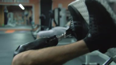 Modern spor salonunda bacak pres makinesi üzerinde egzersiz yapan protez bacaklı motive olmuş sporcuya yaklaş. Fiziksel engelli atletik bir adam profesyonel spor ekipmanları kullanarak antrenman yapıyor..