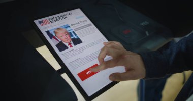 ZAPORIZHYA, UKRAINE - 15 Mart 2024: ZAPORİZHYA, UKRAINE - 15 Mart 2024: İsimsiz bir erkek seçmenin seçim yapması ve Donald Trump 'a oy vermesi için tablet bilgisayar kullanması. ABD