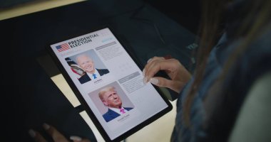 ZAPORIZHYA, UKRAINE - 15 Mart 2024: Seçimlerini yapan kadın seçmen, tablet bilgisayar kullanarak oy verme kabininde Donald Trump 'a oy veriyor. ABD vatandaşı oy kullanma merkezinde