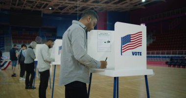 Afro-Amerikalı seçmenler oy verme kabinine geliyor. Çeşitli Amerikan vatandaşları oy kullanma merkezine oy vermeye geldi. ABD başkan adaylarının siyasi ırkları. Ulusal Seçim Günü. Dolly vurdu..