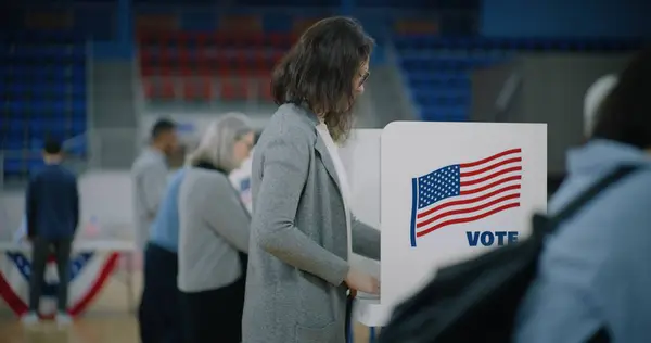 stock image African American voter with bulletin in hands comes to voting booth. Diverse American citizens come to vote in polling station. Political races of US presidential candidates. National Election Day.