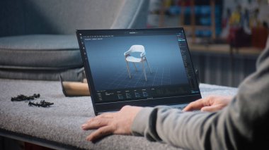 Yaratıcı adam, mobilya tasarımı ve dizüstü bilgisayarda çalışan 3D modelleme için profesyonel yazılım kullanır. Tasarımcı, şık ahşap sandalyenin dijital 3D modelini yaratıyor, marangozluk projesini hazırlıyor.