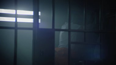 Turuncu üniformalı bir erkek mahkum hapishane hücresinde dolaşıyor, sonra yatağa oturuyor ve İncil okumaya başlıyor. Dini tutuklu hapiste hapis yatıyor. Gözaltı merkezi ya da ıslah evi.