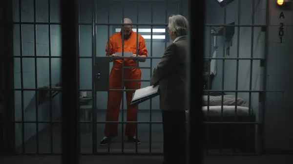 身穿橙色制服的囚犯在监牢里走着 与律师交谈 阅读律师合同 罪犯因犯罪在狱中服刑 拘留中心或教养所 — 图库照片