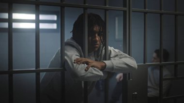Depresyondaki Afro-Amerikalı dövmeli genç hapisteki hücrede kameraya bakıyor. Genç mahkûm, suçtan hapis yatıyor. Çocuk ıslahevi ya da ıslah evi.
