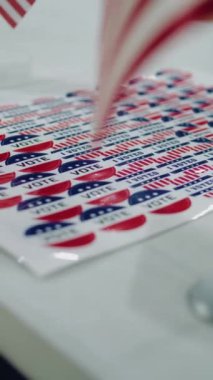 Amerika Birleşik Devletleri 'nde dikey çekim. Masanın üzerinde Amerikan bayrağı logosu ve yazıtları olan vatansever çıkartmaları kapatın. Başkanlık yarışı ve seçim haberleri. Vatandaşlık görevi