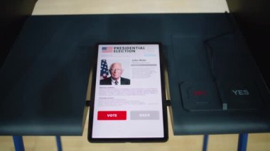 Oy verme kabininde tablet bilgisayarlı. Ekranda gösterilen ABD başkan adayı ve oy kullanma düğmeleri hakkında bilgi. Modern dijital oylama teknolojisi. ABD 'de seçimler.