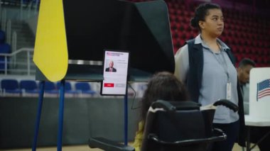 Özürlü ABD vatandaşı oy kullanmak için tablet bilgisayara bakıyor. Kadın seçmen, SMA tekerlekli sandalyedeki kadın oy kullanma kabininde oy veriyor. Amerika Birleşik Devletleri Başkanlık Seçimi.