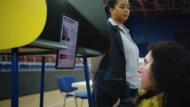 車椅子に身体障害のある女性は 投票のためにリモートコントロールとタブレットコンピュータを使用します 投票所でSma投票をした米国の女性有権者 アメリカ合衆国大統領選挙 — ストック動画