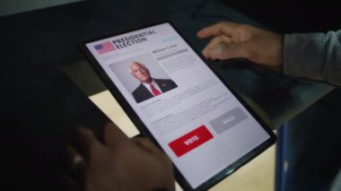 Afro-Amerikalı erkek, erkek seçmen tablet bilgisayar kullanarak oy verme kabininde ABD başkan adayı için oy veriyor. Amerikan vatandaşı oy kullanma merkezinde. Amerika Birleşik Devletleri Seçim Günü.