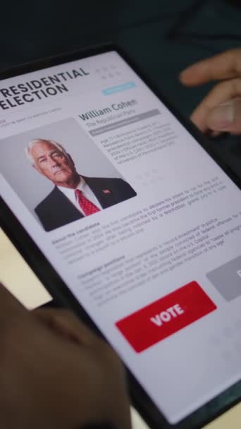 アフリカ系アメリカ人男性の垂直撮影 タブレットコンピュータを使用して投票ブースで米国大統領候補に投票する男性有権者 ポーリング ステーションのアメリカ市民 アメリカ合衆国選挙の日 — ストック動画