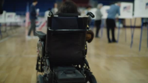 坐轮椅的身体残疾妇女到投票站投票 在地板上签名投票 美国总统候选人的政治竞争 公民义务和爱国主义 Dolly Shot — 图库视频影像