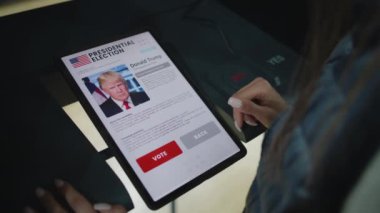 ZAPORIZHYA, UKRAINE - 15 Mart 2024: Tablet bilgisayar kullanarak oy verme kabininde kadın seçmenin seçim yapmasına ve Joe Biden 'a oy vermesine yakın durun. Başkanlık döneminde oy kullanma merkezinde Amerikan vatandaşı