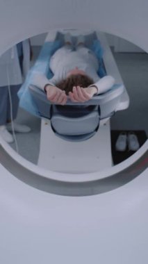 Tomografide, PET 'te ya da MRI makinesinde yatan hastanın dikey görüntüsü. Gelişmiş aletler, tıbbi tesiste detaylı muayene için vücudu ve beyni tarıyor. Yüksek teknoloji, modern tıp laboratuarı. Sağlık hizmetleri kavramı.