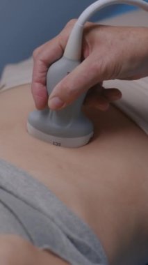 Tıbbi uzman ileri tıbbi ekipmanlar kullanarak hastaya mide ultrasonu yapıyor. Beyaz kadın modern klinikte abdominal organların sonografi testinden geçiyor. Dikey