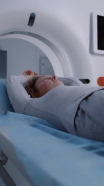 Tomografide, PET 'de ya da MR' da yatarken, yatağı tararken ve makinenin içinde hareket ederken dikey görüntü. Yüksek teknolojili modern ekipmanlar kullanarak hasta vücudunu ve beynini tarıyorum. Gelişmiş teknolojili tıbbi tesis..