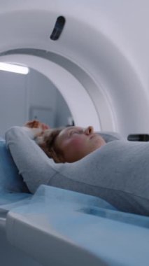 Tomografide, PET 'de ya da MR' da yatarken, yatağı tararken ve makinenin içinde hareket ederken dikey görüntü. Yüksek teknolojili modern ekipmanlar kullanarak hasta vücudunu ve beynini tarıyorum. Gelişmiş teknolojili bir tıp laboratuvarı..