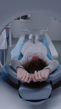 Tomografide, PET 'de ya da MR' da yatarken, yatağı tararken ve makinenin içinde hareket ederken dikey görüntü. Yüksek teknolojili modern ekipmanlar kullanarak hasta vücudunu ve beynini tarıyorum. Gelişmiş teknolojili tıbbi tesis..