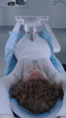 Kadın hasta MRI veya CT tarama makinesinde ameliyat için bekliyor. Beyaz kadın bilgisayarlı tomografi araştırmasından geçiyor, modern ve gelişmiş tıbbi ekipmanlarla kliniğe gidiyor..
