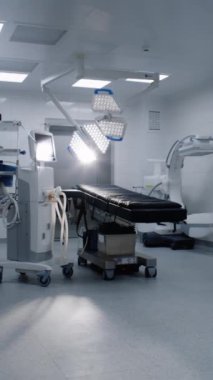 Modern hastanedeki ameliyat odasının dikey görüntüsü ve gelişmiş ameliyat ekipmanları. Ameliyat masası, LED lambalar, yaşam desteği ve anestezi makinesi. Klinikte ya da tıbbi tesiste operasyon bloğu.