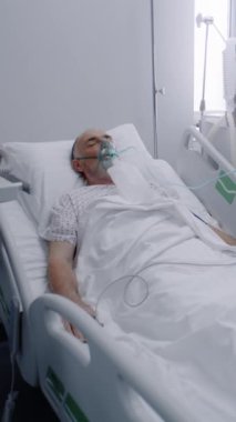 Oksijen maskeli hasta yaşlı adam hastane koğuşunda uyuyor. Akciğer solunum sırasında eski bir hasta. Klinikteki donanımlı acil servis. Modern tıp merkezindeki yoğun bakım Coronavirus Bölümü.