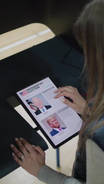 Zaporizhya Ukraine March 2024 白人女性 女性投票者は タブレットコンピュータを使用して投票ブースでドナルド トランプに選択と投票を行います 大統領時代の投票所にいる米国市民 — ストック動画