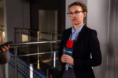 Elinde mikrofon olan bir kadın gazeteci haber için bir politikacıyla röportaj yapmaya hazırlanıyor.
