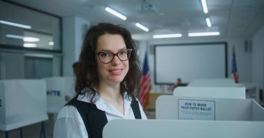 Amerikan kadınlarının oy verme kabinindeki başkan adayı için oy verirken yakın plan çekimleri, sonra gülümseyip kameraya bakarken. ABD 'de Ulusal Seçim Günü' nde ABD vatandaşı.