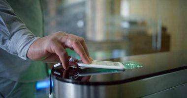 Beyaz adam ya da iş adamı elektronik kartla kapılardan iş merkezine giriyor. Modern ofis binasında otomatik tarama ve kimlik tespiti için dokunmatik panele sahip turnike.