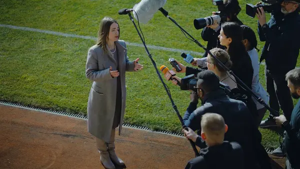 サッカーチームの女性ディレクターがプレス質問に答え 重要な試合前にサッカー場の近くでインタビューを行った 投資家やビジネスマンは ニュースジャーナリストによって混雑した インスピレーションスピーチ — ストック写真