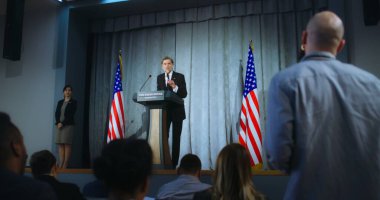 ABD başkan adayı kampanya konuşması yapıyor, soruları cevaplıyor, röportaj veriyor. Amerikalı cumhuriyetçi politikacı basınla yaptığı görüşmede performans sergiliyor. Seçim günü. Amerikan bayraklı arkaplan.